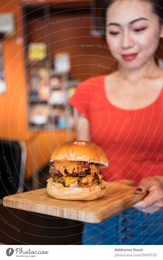 Asiatische Kellnerin serviert Burger im Cafe Café dienen Frau sorgen lecker Fastfood geschmackvoll Dienst ethnisch asiatisch hölzern Lebensmittel Mahlzeit Glück
