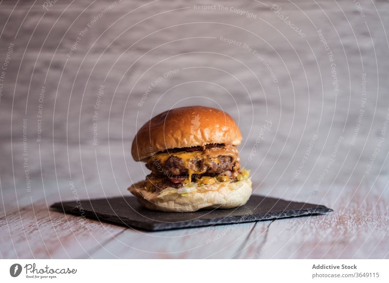 Leckerer Burger auf Schiefertafel im Cafe appetitlich Café lecker dienen Hamburger Kotelett geschmackvoll Fastfood Küche Holzplatte hölzern Tisch Saucen