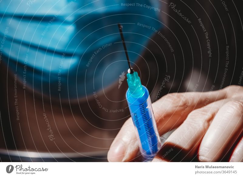 Covid-19 Impfstoff in der Hand des Arztes mit Maske Nahaufnahme auf schwarzem Hintergrund Coronavirus 2020 Atemschutzmaske schwarzer Hintergrund Klinik