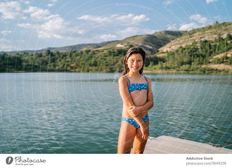 Verspieltes Mädchen steht im Pier am See Teich Sommer Feiertag Urlaub genießen Kind Bikini Wasser sich[Akk] entspannen Natur spielerisch Freude Sommerzeit