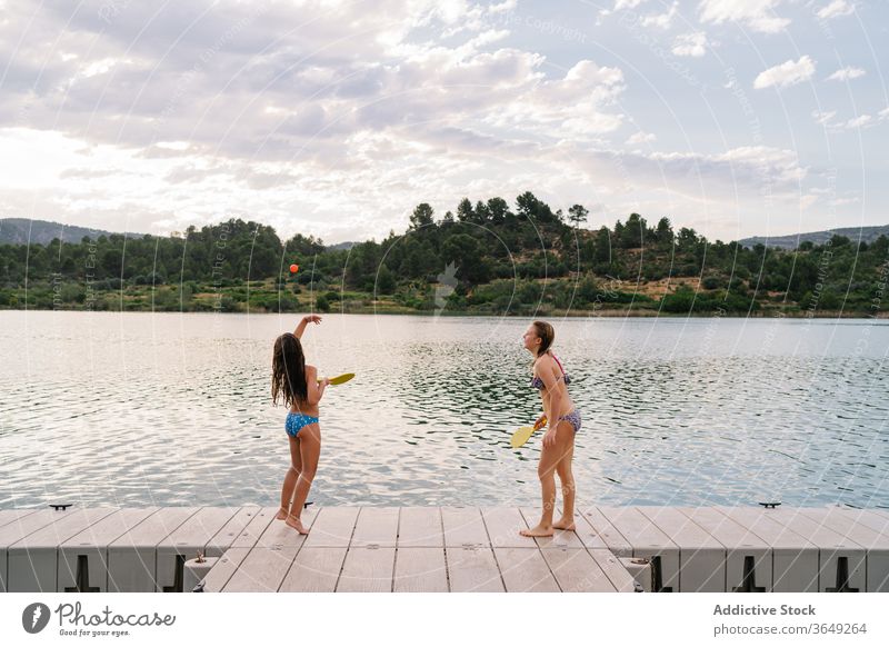 Glückliche Schwestern spielen Strandtennis auf dem Pier Tennis See Mädchen aktiv genießen Feiertag Spaß haben Bikini Sommer Ball Remmidemmi Teenager Kai hölzern