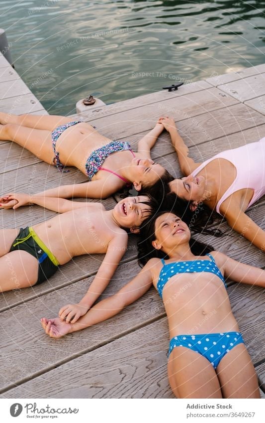 Glückliche Geschwister und Mutter am Kai liegend Kinder Urlaub Sommer Pier sich[Akk] entspannen Stern Form Lügen Badebekleidung Inhalt ruhen Händchenhalten