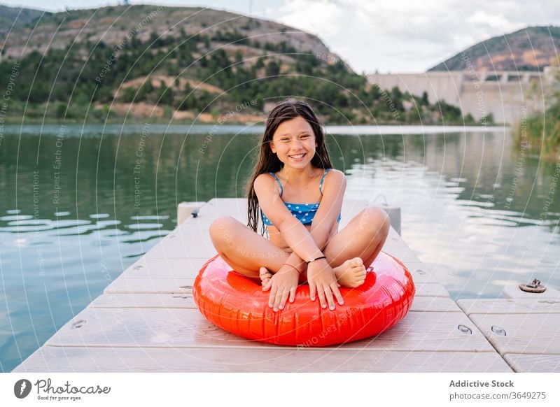 Sorgloses kleines Mädchen auf Gummiring am Kai See Pier Kind sich[Akk] entspannen Ring Feiertag sorgenfrei Lächeln aufblasbar bezaubernd Wasser hölzern Sommer