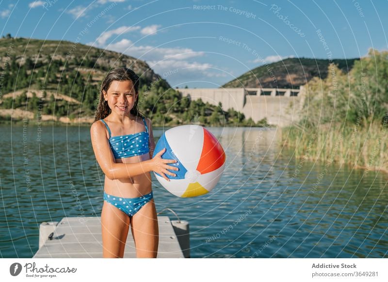 Verspieltes Mädchen steht im Pier am See Beachball spielen Teich Sommer Feiertag Urlaub genießen aufblasbar Gummi Kind Bikini Wasser sich[Akk] entspannen Natur