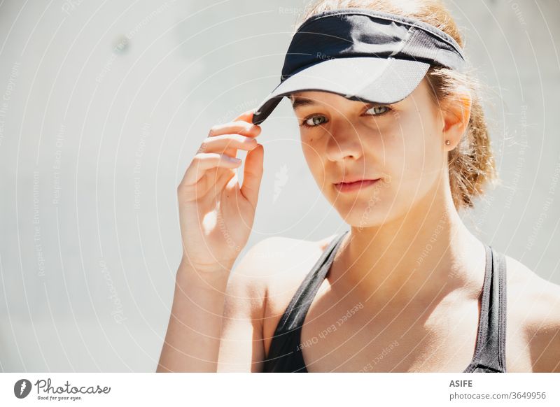 Porträt einer schönen, jungen, sportlichen Frau mit Schirmmütze an einem warmen Tag Sport Model Gesicht posierend rennen vereinzelt Glück Lächeln Läufer Wand