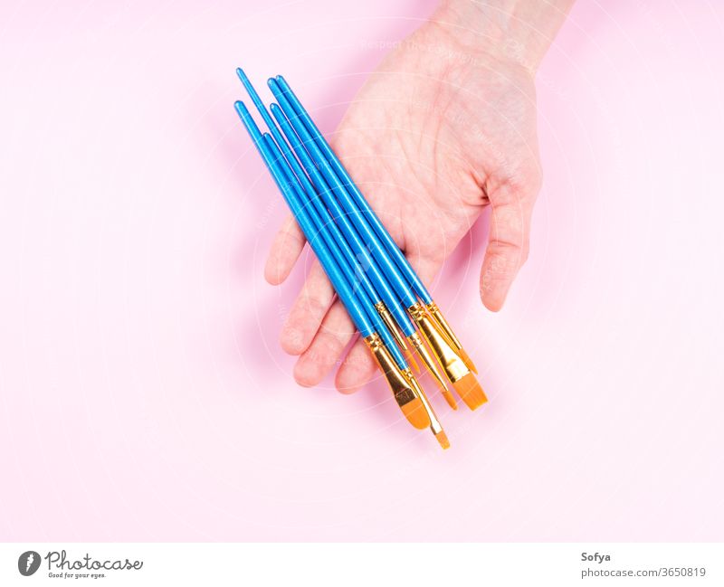 Blaue Pinsel in Frauenhand auf Rosa Kunst Pinselblume Kunstangebot rosa Künstler flache Verlegung Borste Hand Malerei Halt anders Hintergrund blau Klasse Bürste