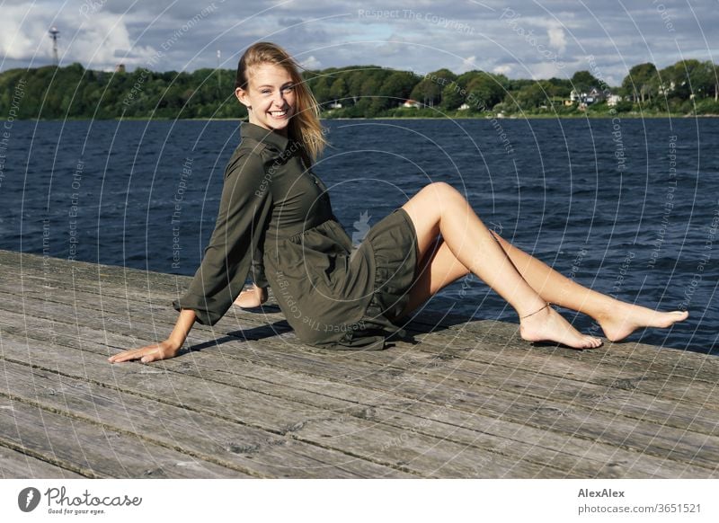 Ganzkörper- Portrait einer jungen, blonden, barfüßigen Frau auf Holzsteg im Meer junge Frau schön schlank langhaarig windig ästhetisch Sommer Ausflug