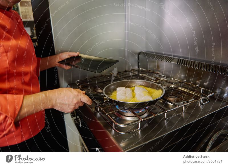 Gesichtsloser Koch beim Schmoren von Fischfilets in Butter in der Küche Küchenchef schmoren Erdöl Prozess kulinarisch Pfanne Herd Gas vorbereiten oliv zerlaufen