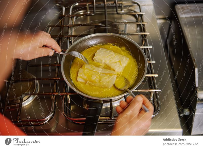 Gesichtsloser Koch beim Schmoren von Fischfilets in Butter in der Küche Küchenchef schmoren Erdöl Prozess kulinarisch Pfanne Herd Gas vorbereiten oliv zerlaufen