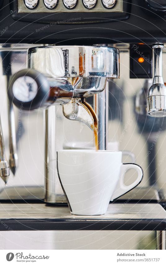 Moderne Kaffeemaschine gießt Kaffee in eine weiße Tasse im Restaurant Maschine eingießen modern Gerät Aroma Prozess professionell Kaffeehaus frisch Geschmack