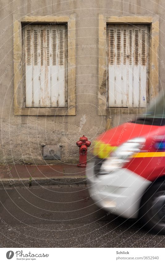 Hausfassade in Lothringen Metz mit Hydrant bei Regenwetter Notarztwagen rast ins Bild Fassade Fenster Rettungswagen zwei Klappläden geschlossen Faltschiebeladen