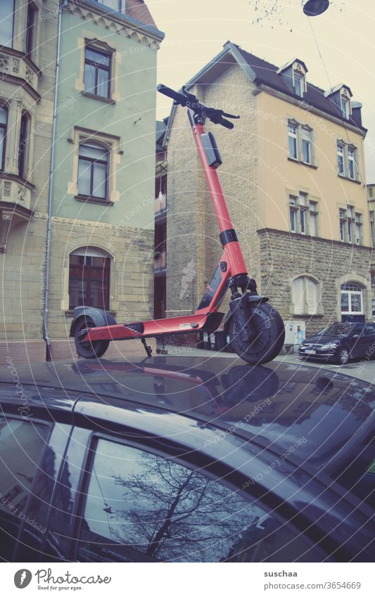 jemand hat einen e-roller auf einem auto geparkt E-Roller Auto Stadt Häuers Fenster Wohngegend urban Unfug Blödsinn grober Unfug Sachbeschädigung Streich