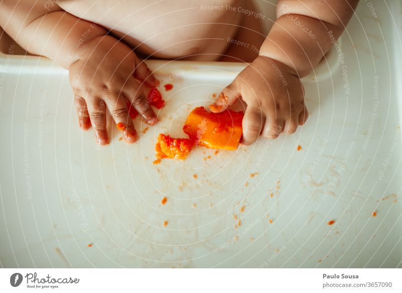 Nahaufnahme eines Babys, das Obst isst Hände Hand Körperteil Säuglingsalter Essen Frucht Papaya Gesunde Ernährung Innenaufnahme Farbfoto rot frisch süß genießen