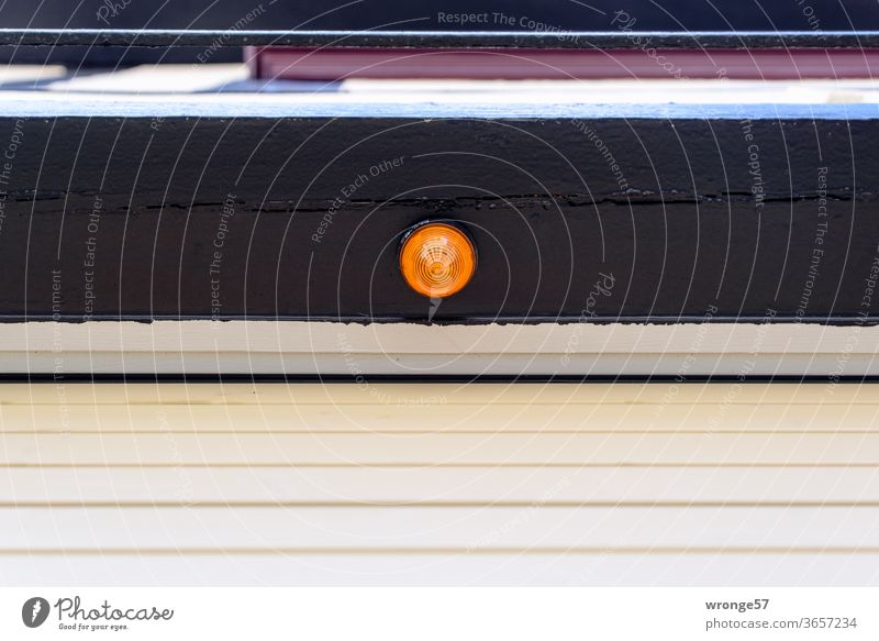 Orange Signallampe an einem Balken über einem geschlossenen automatischen Garagentor orange Elektrogerät Menschenleer Außenaufnahme Farbfoto Tag Wand Gebäude
