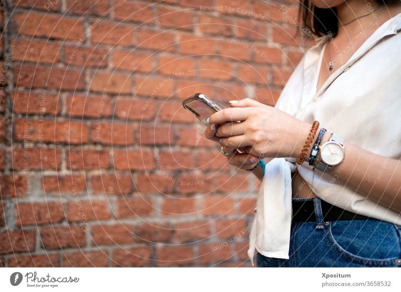 Seitenansicht einer Nahaufnahme einer nicht erkennbaren Frau mit ihrem Smartphone allein attraktiv schön Schönheit Funktelefon Großstadt Mitteilung Arbeitsweg