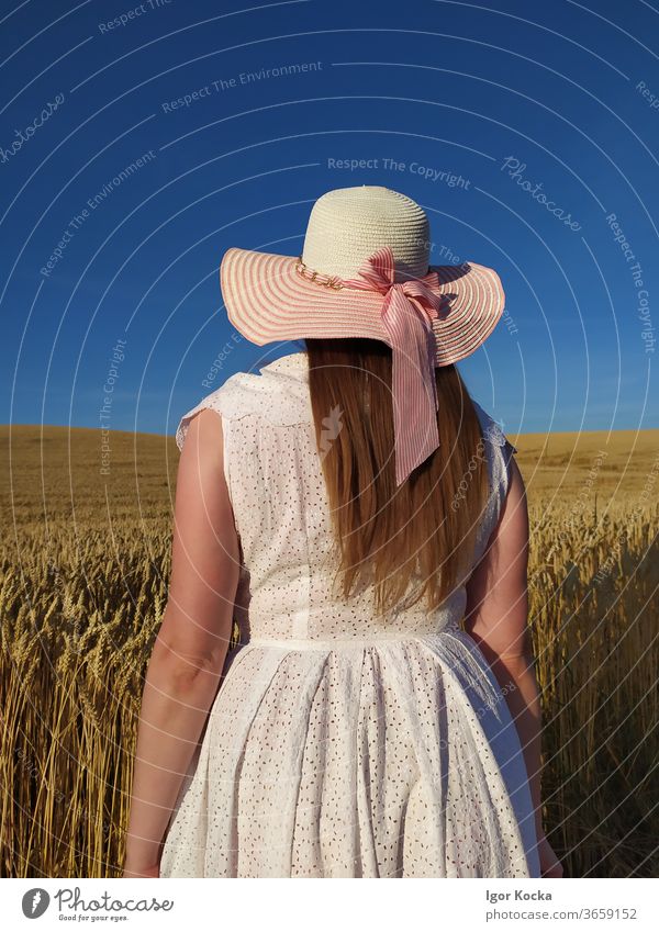 Rückansicht der Frau im Feld gegen den Himmel Bauernhof Hut Feldfrüchte blau Sonnenlicht Porträt Mode weißes Kleid Ländliche Szene Ackerbau