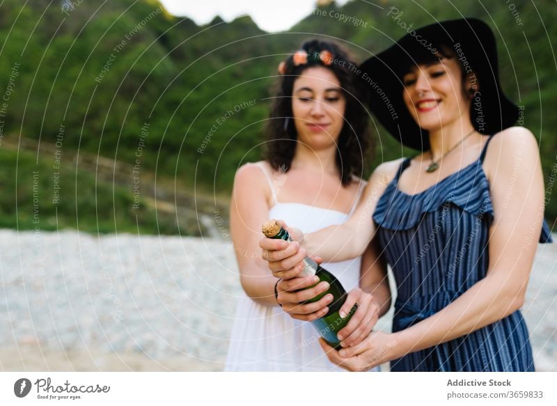 Schwules Paar beim Öffnen einer Flasche Champagner lesbisch Strand offen feiern Alkohol lgbt Zusammensein Frauen Freundin Wochenende Sommer Lächeln Glas trinken