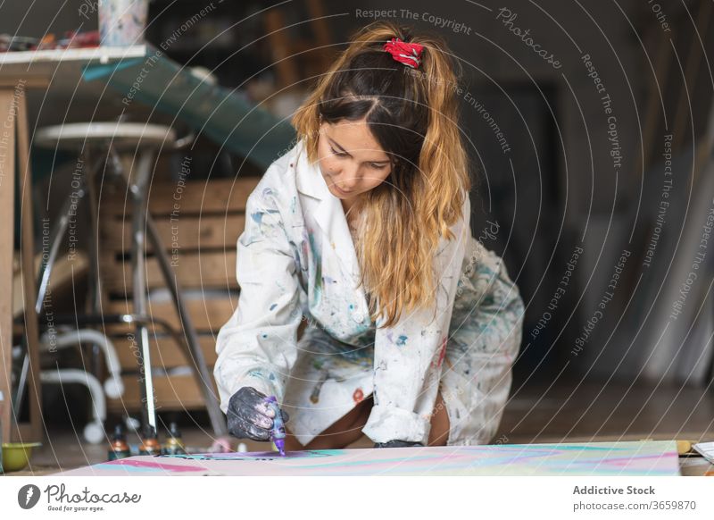 Fröhliche Malerin lacht beim Betrachten eines farbenfrohen Bildes Anstreicher Kunst Lachen Handwerk Talent liquide Barfuß Handschuh Werkstatt Künstler Papier