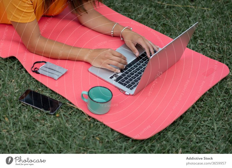 Anonyme Frau benutzt Geräte beim Camping Lager Apparatur benutzend modern Zelt Tourist positiv Natur jung lässig Laptop Wiese liegend ruhen Urlaub Handy