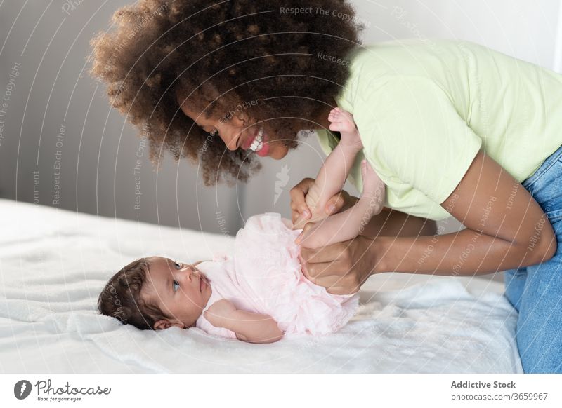Zufriedene ethnische Mutter spielt mit Baby Säugling spielen Frau Angebot neugeboren bezaubernd Inhalt Spaß haben heimwärts Afroamerikaner schwarz heiter Eltern