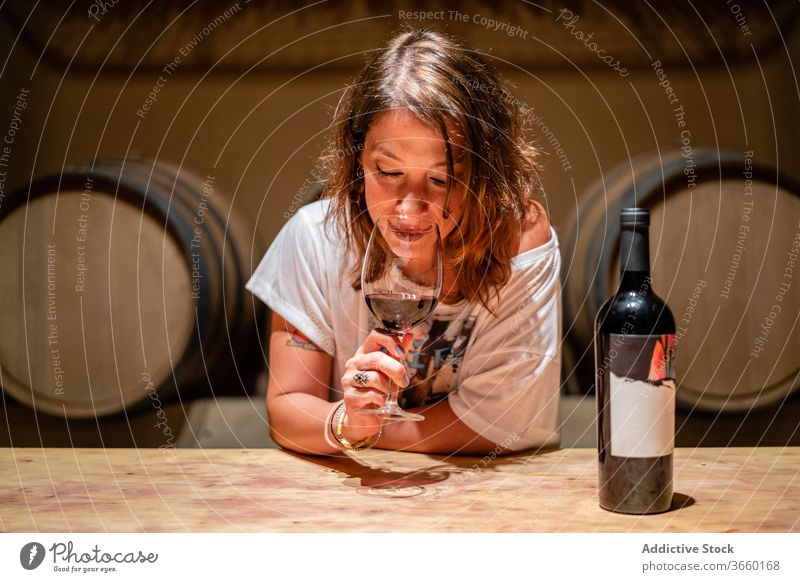 Entspannte Frau riecht Rotwein im Glas im Weingut genießen riechen aromatisch Verkostung degustieren gemütlich sich[Akk] entspannen Inhalt lässig