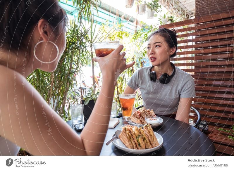Asiatische Freundinnen auf der Terrasse im Cafe genießen Wochenende Café Sommer Frauen geschmackvoll Dessert trinken Zusammensein ethnisch asiatisch lecker