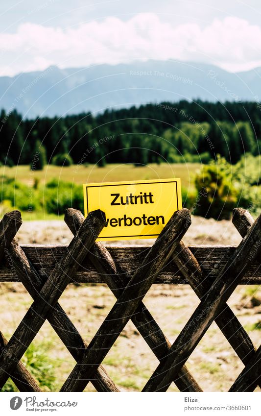 Landschaft mit Wald und Bergen und davor ein Zaun und ein Schild mit der Aufschrift "Zutritt verboten". Unerwünschter Tourismus. unerwünscht Alpenvorland Bayern