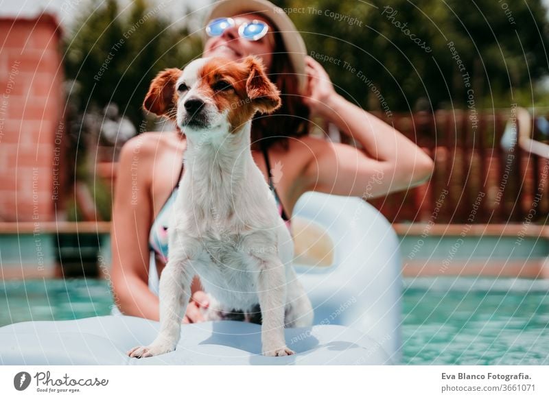 glückliche Frau und Hund in einem Pool, die sich amüsieren. sitzend auf einem Schlauchboot. Sommerzeit Schwimmbad aufblasbar Blauwasser Liebe jack russell Hut