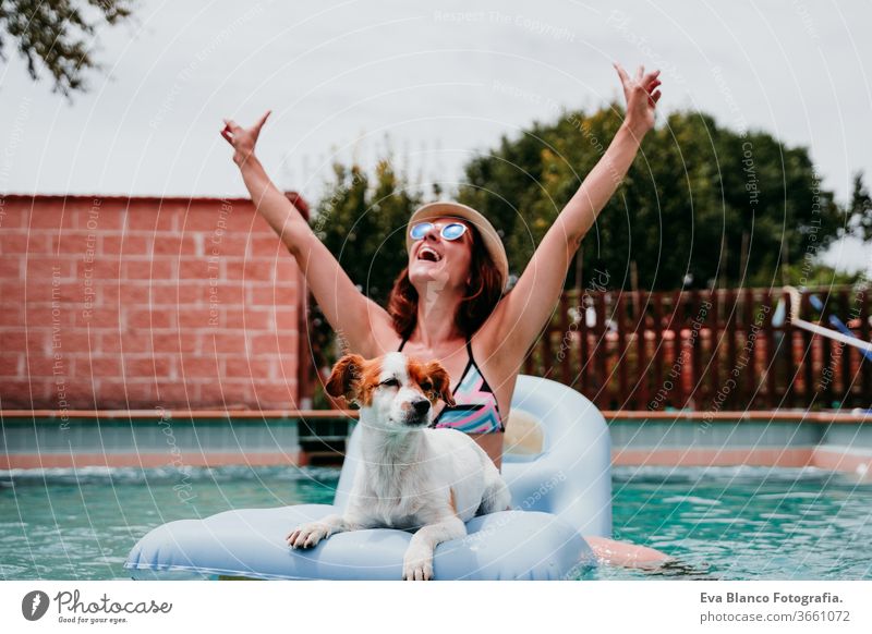 glückliche Frau und Hund in einem Pool, die Spaß haben. Hund sitzt auf einem Schlauchboot und spielt mit seinem Besitzer. Sommerzeit Schwimmbad aufblasbar