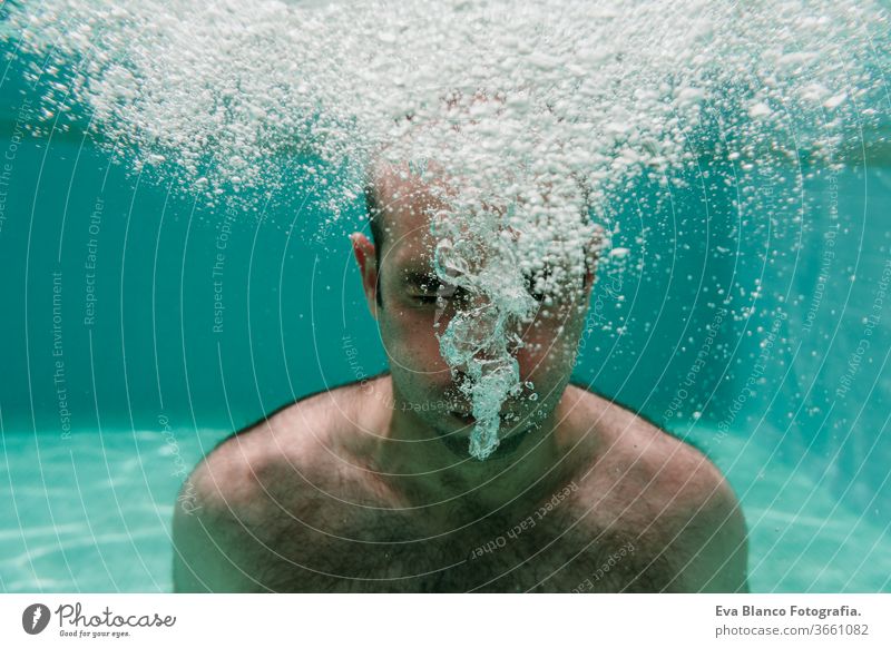 junger Mann taucht unter Wasser in einem Pool und macht Seifenblasen, Sommer und Spaß Schwimmsport Blasen Kaukasier Sinkflug Lifestyle übersichtlich Gesundheit