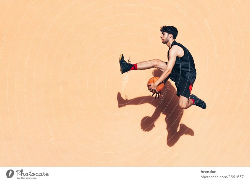 Basketballspieler, der mit dem Ball in der Hand vor eine Wand springt Sport Konkurrenz springen springend Bewegung Spiel sportlich wettbewerbsfähig spielen