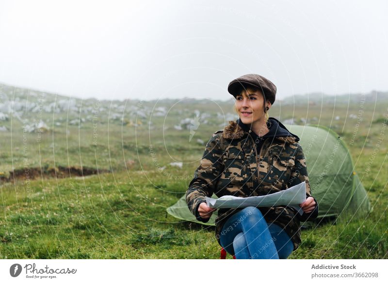 Fokussierte Frau mit Karte sitzt in der Nähe des Zeltcamps in der Natur Lager Landkarte navigieren Abenteuer Konzentration Örtlichkeit Reisender Fernweh