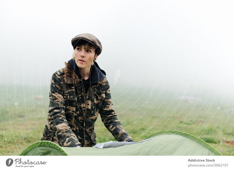 Frau mit Karte steht in der Nähe des Zeltcamps in nebliger Landschaft Landkarte Lager navigieren positiv Natur Örtlichkeit Route Anleitung Nebel reisen