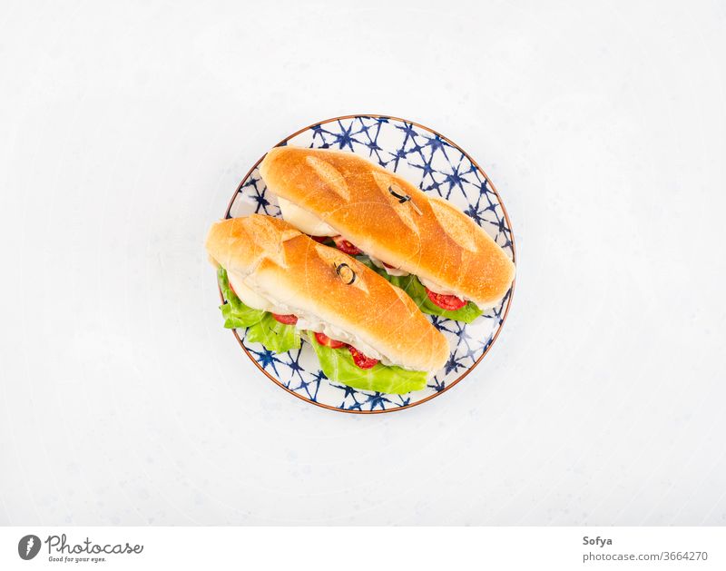 Baguette-Sandwich mit Tomaten und Käse Belegtes Brot U-Boot Mittagessen Sub hoagie flache Verlegung geschmolzen Gemüse Draufsicht Salatbeilage hölzern