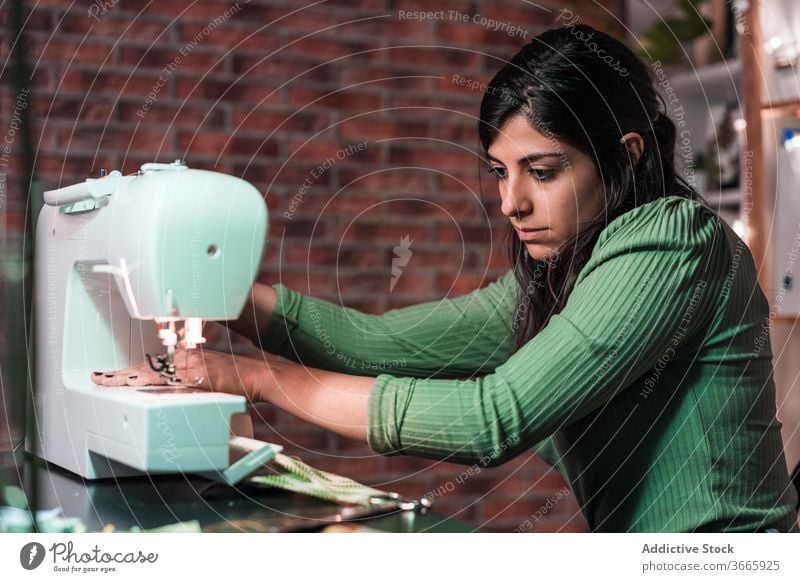 Schneidernähen auf einer Maschine in der Nähe einer Ziegelwand im Atelier Nähmaschine Basteln Probe Muster Lampe Kleinunternehmen Backsteinwand Werkstatt Gewebe