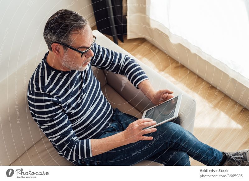 Erwachsener Mann benutzt Tablette zu Hause selbstbewusst Technik & Technologie Kaukasier Arbeit Liege benutzend modern nachdenklich Entertainment Browsen