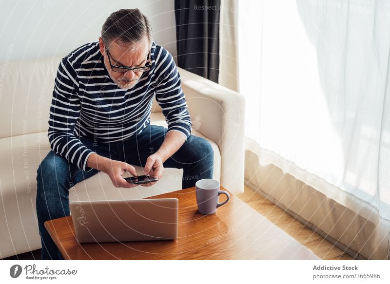 Erwachsener Mann benutzt Smartphone und Laptop selbstbewusst Technik & Technologie Kaukasier Arbeit COVID19 Liege Mitteilung Coronavirus benutzend Handy modern
