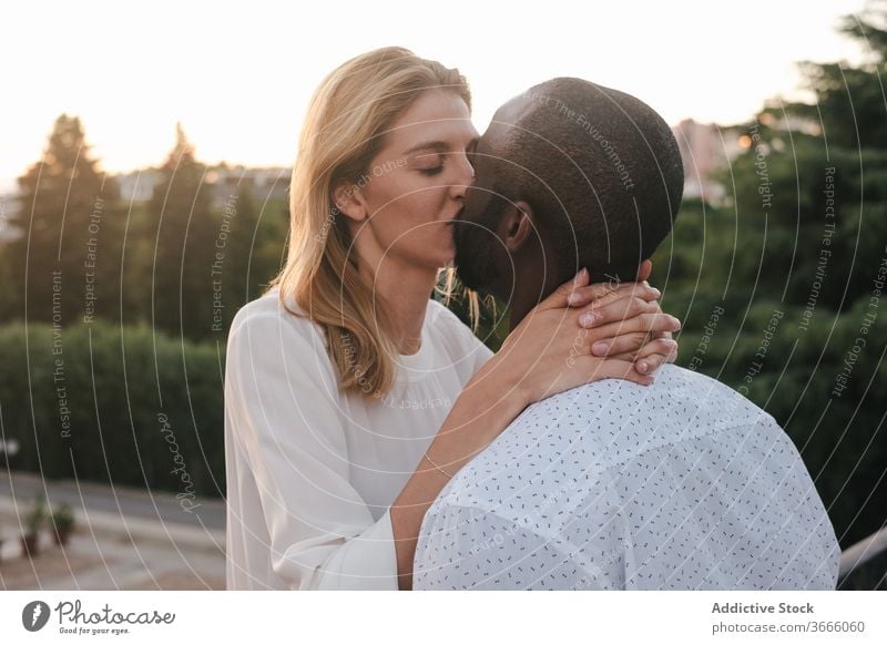 Glückliches, verschiedenartiges Paar küsst sich auf der Straße Kuss Bonden romantisch positiv Partnerschaft Liebe Zuneigung Umarmen modern lässig urban