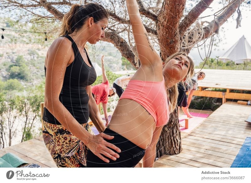 Konzentrierte Frau macht Yoga mit Trainerin im Park Frauen Seitenwinkel parsvakonasana abstützen Ausbilderin Klasse Asana Wellness Gesundheit Hilfsbereitschaft