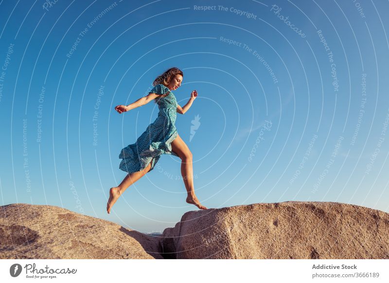 Aktive junge Frau rennt bei Sonnenuntergang auf riesigen Steinen springen laufen felsig Klippe Glück Stil Erholung Freiheit Sommer Blauer Himmel Feiertag heiter