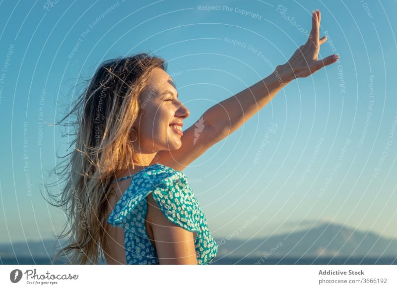 Lächelnde junge Touristin erholt sich bei Sonnenuntergang im ruhigen Meer Frau Erholung Meeresufer genießen Glück Reisender Sommer Urlaub heiter wolkenlos