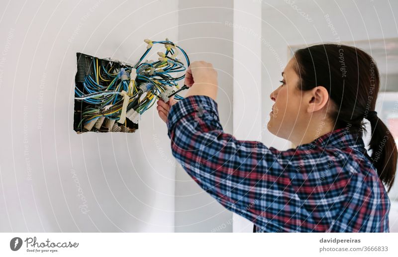 Elektriker, der an der Elektroinstallation eines Hauses arbeitet Elektrotechniker Frau Elektromonteur Installation Schraubendreher verbindend Elektrischer Draht