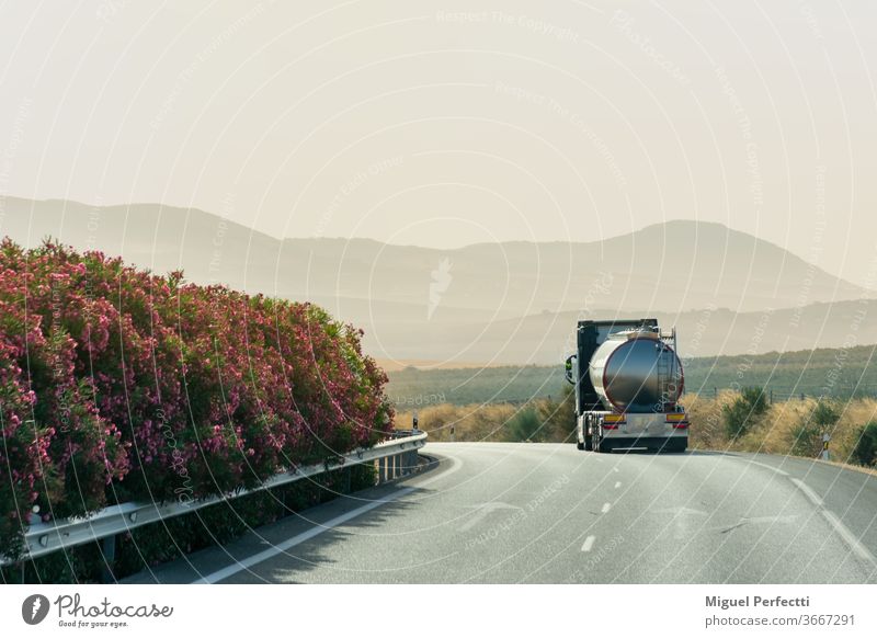 Tankwagen fährt auf der Autobahn mit einem Hintergrund von Bergen bei Sonnenaufgang Lastwagen Straße reisen Landschaft Natur Flüssigtransport Nebel