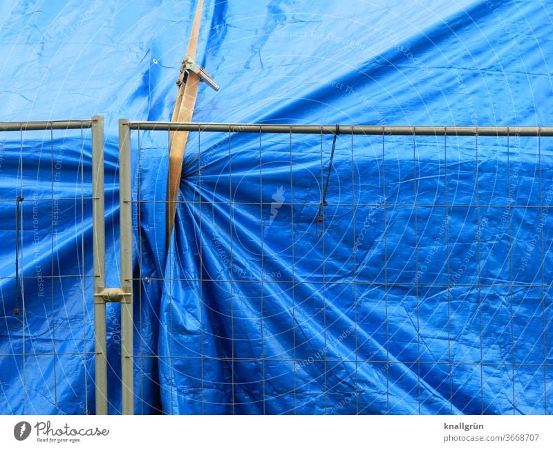 Große blaue Plane gesichert mit einem Spanngurt hinter einem Bauzaun aus Metall Schutz Sicherheit Abdeckung Strukturen & Formen Baustelle Kunststoff silber