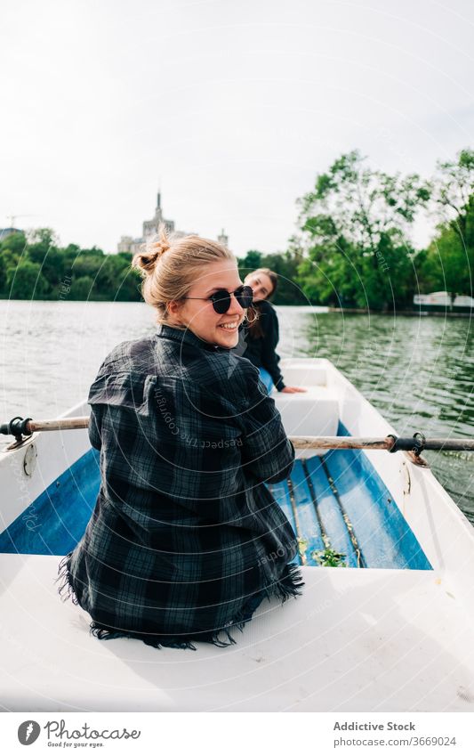 Fröhliche Freundinnen rudern auf dem Boot auf dem See Frauen Rudern positiv heiter sculling Lächeln Natur Aktivität friedlich Windstille sich[Akk] entspannen
