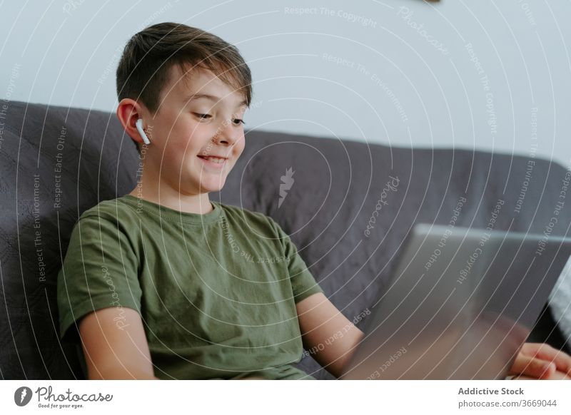 Bezauberndes Kind mit Videoanruf auf Laptop zu Hause Junge Video-Chat Kommunizieren Wellenhand Sofa heimwärts heiter Anruf Apparatur Glück Internet Gerät wenig