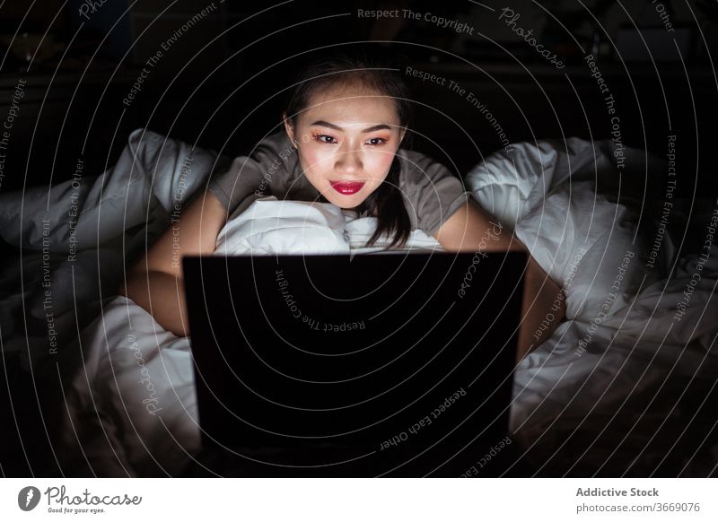 Asiatische Frau im Bett liegend mit Laptop in der Nacht sich[Akk] entspannen Internet Komfort heimisch benutzend Gerät Apparatur Netbook genießen Optimist