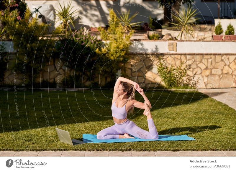 Flexible Frau macht Yoga in King Pigeon Pose üben eka pada rajakapotasana Hof Unterlage ruhig beweglich Harmonie aktive Kleidung Asana Wellness sitzen schlank