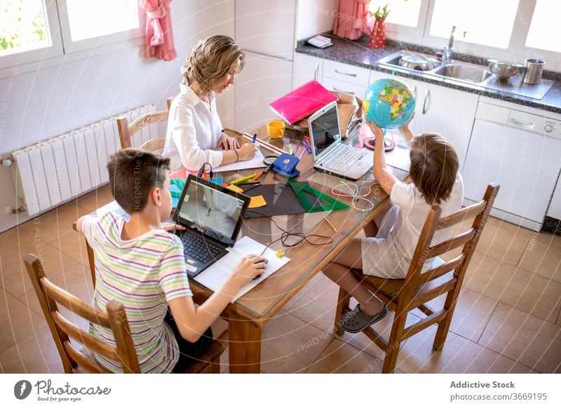 Seriöse Geschäftsfrau surft im Internet auf Laptop mit Kindern zu Hause Mutter Tippen Hausaufgabe Bildung lernen sich auf die Hand lehnen benutzend Apparatur