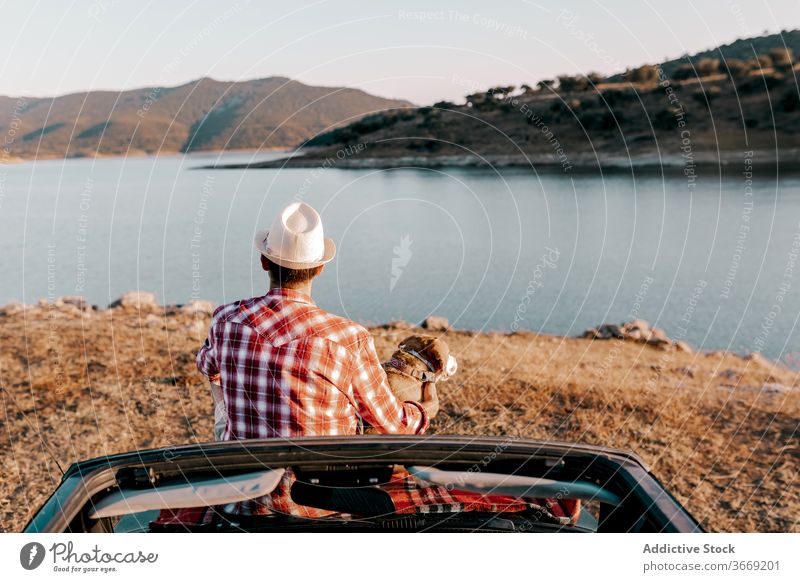 Anonymer Tourist mit Hovawart genießt die Natur auf dem Auto sitzend im Sonnenlicht Hund bewundern Fluss Berge u. Gebirge PKW Urlaub Schönheit idyllisch